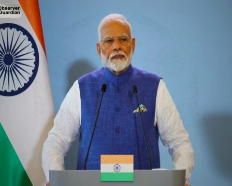 Man speaking at podium with flag. modi